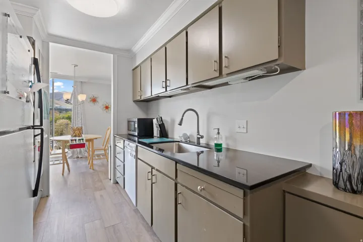 Kitchen featuring ornamental molding, white appliances, light wood-style flooring, pendant lighting, and expansive windows