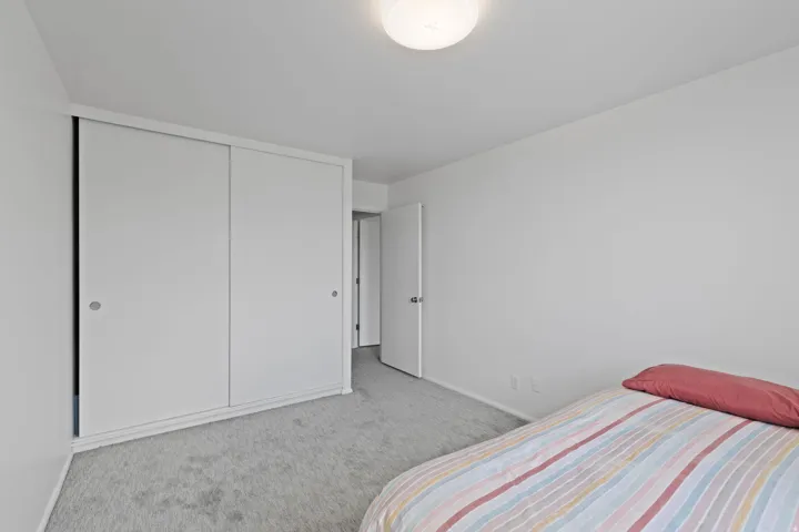Bedroom with light carpet and a closet
