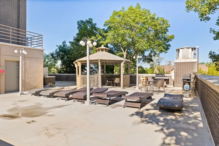 View of patio with an outdoor brick fireplace, a gazebo, and grilling area
