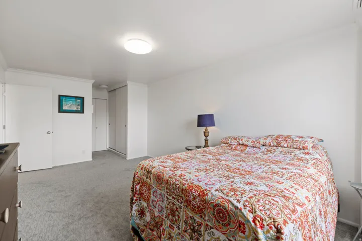 Bedroom with light colored carpet, ornamental molding, and a closet