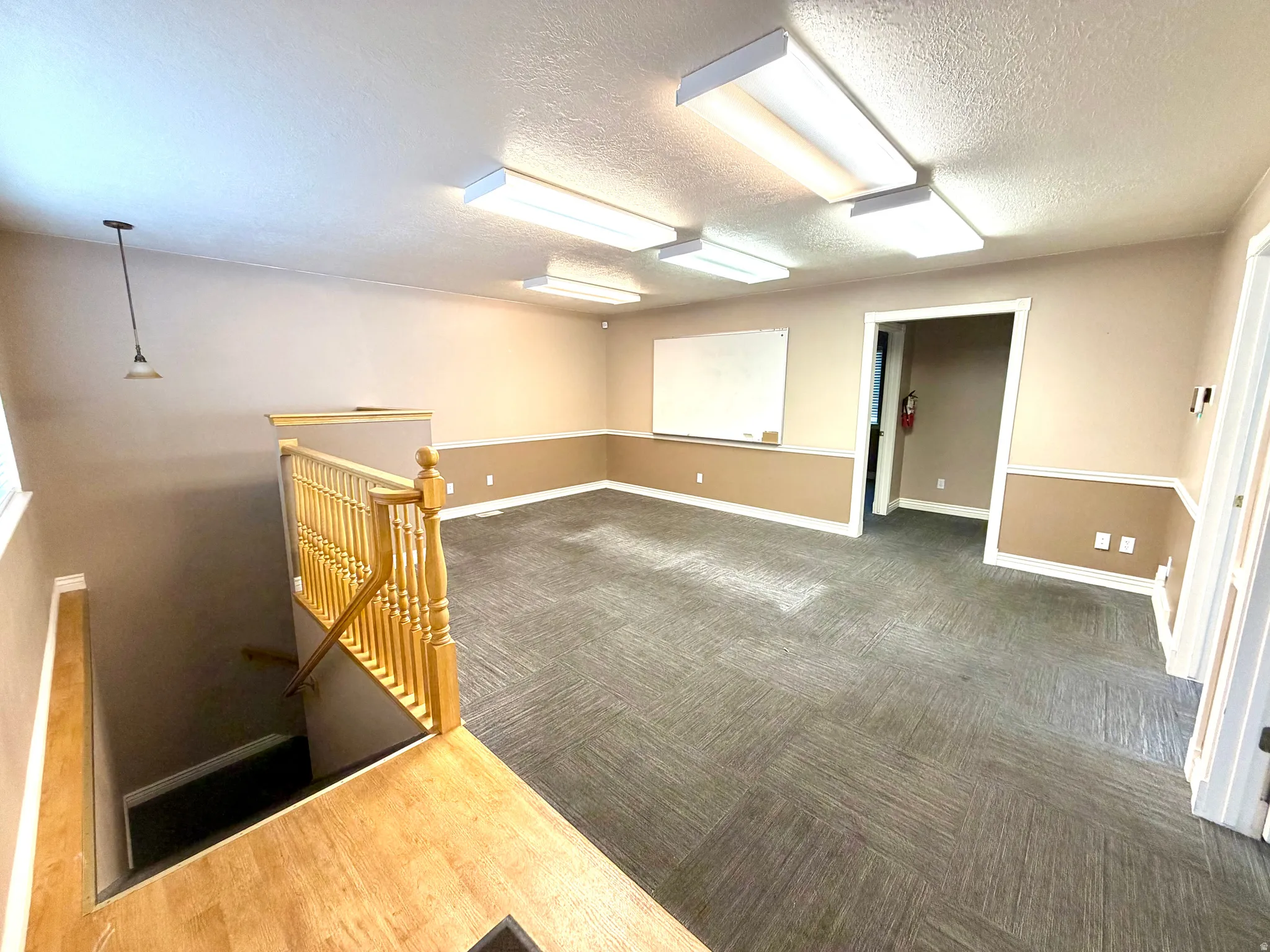Empty room with a textured ceiling and dark colored carpet - Previously used as a conference room