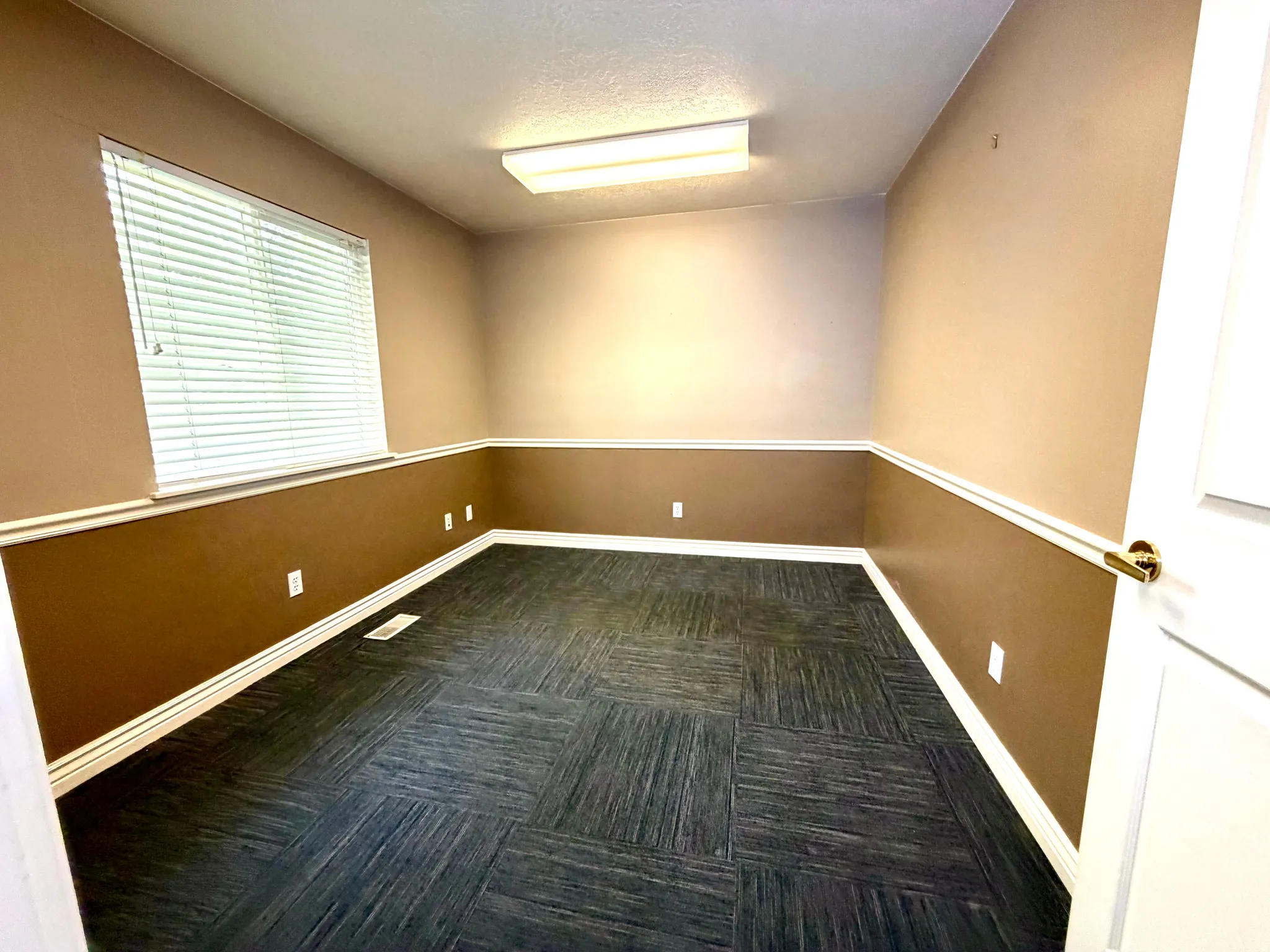 Empty room with dark carpet and a textured ceiling