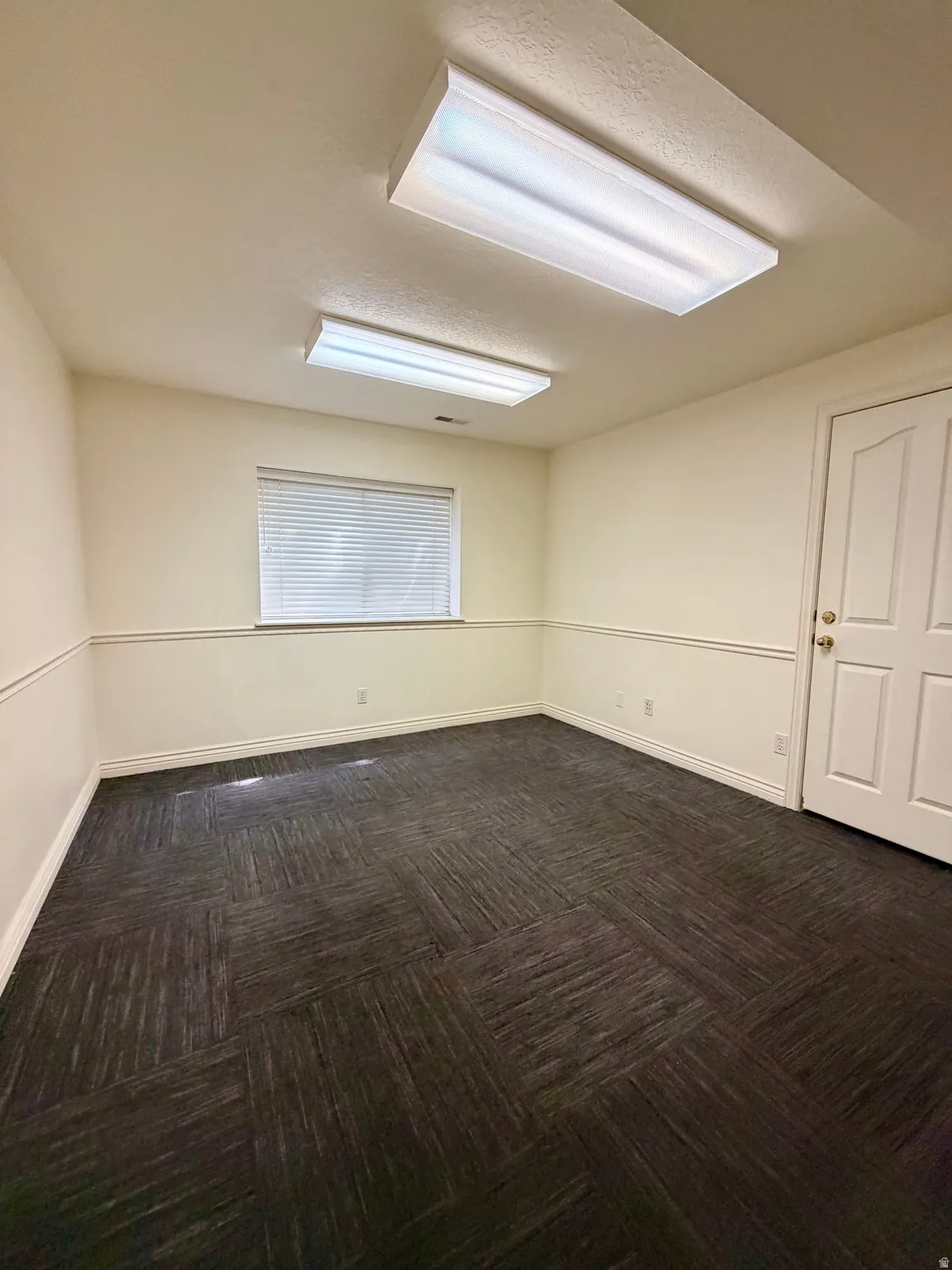 Unfurnished room with dark carpet and baseboards