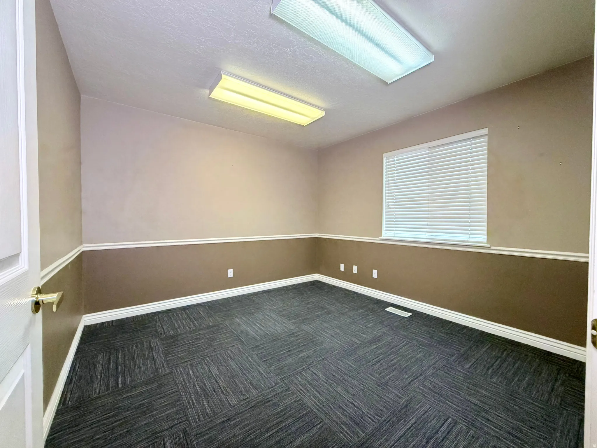 Unfurnished room with dark carpet and a textured ceiling