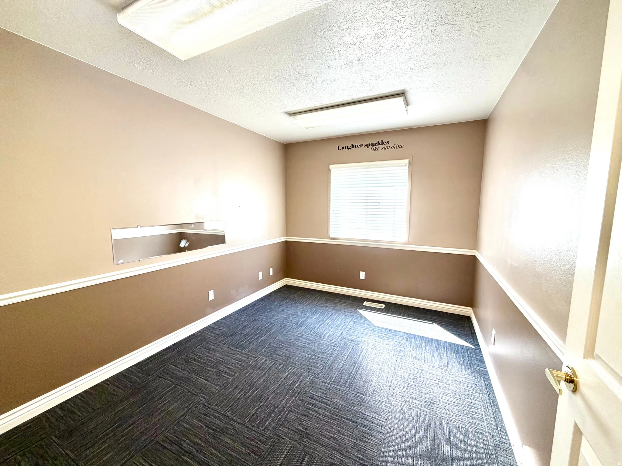 Spare room featuring dark carpet and a textured ceiling