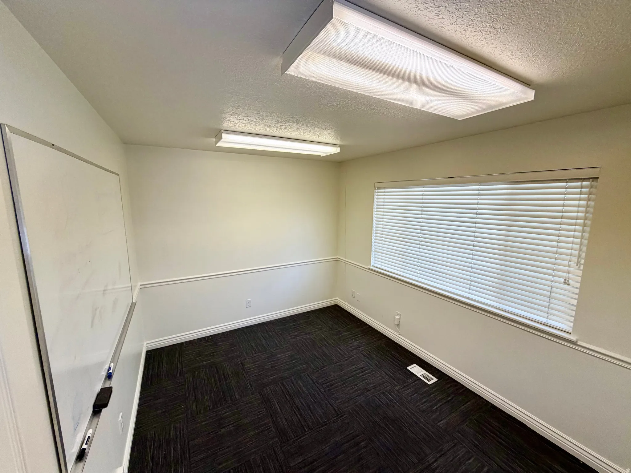 Unfurnished room featuring a textured ceiling and dark colored carpet