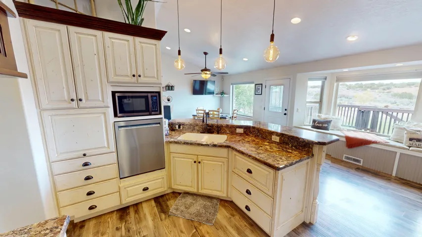 Kitchen featuring cream cabinetry, dark stone countertops, open floor plan, and vaulted ceiling