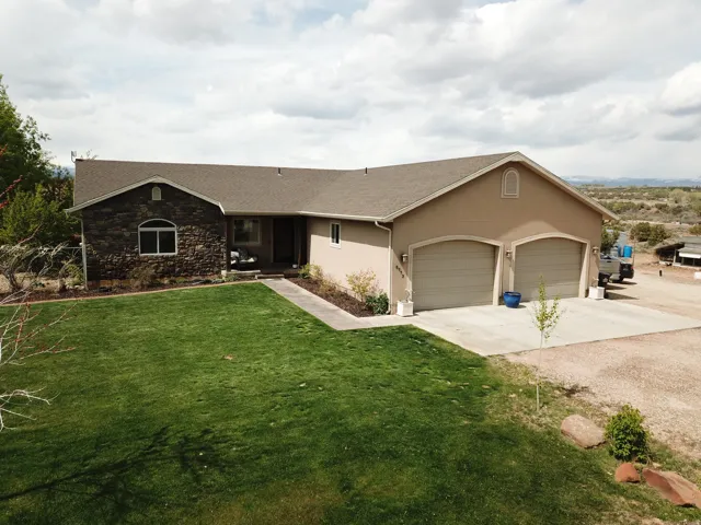 Ranch-style house featuring driveway, stucco siding, roof with shingles, and a front lawn