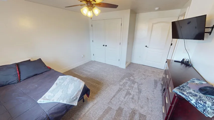 Bedroom with light carpet, a closet, and a ceiling fan
