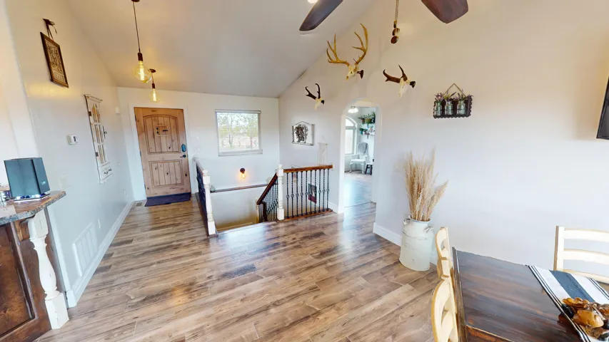 Entryway with arched walkways, vaulted ceiling, light wood-style floors, and ceiling fan