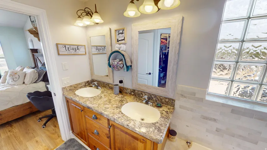 Primary Ensuite bathroom featuring double vanity, light wood finished floors, and a garden tub