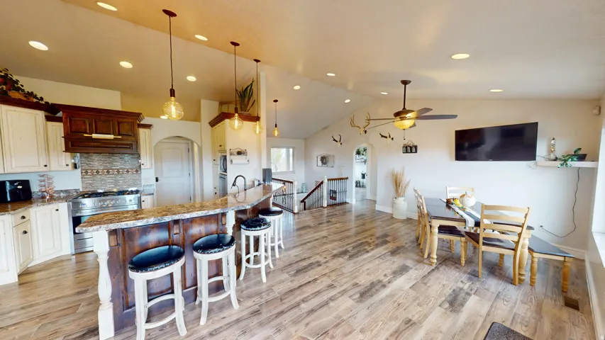 Kitchen featuring arched walkways, light stone counters, a kitchen breakfast bar, stainless steel appliances, and hanging light fixtures