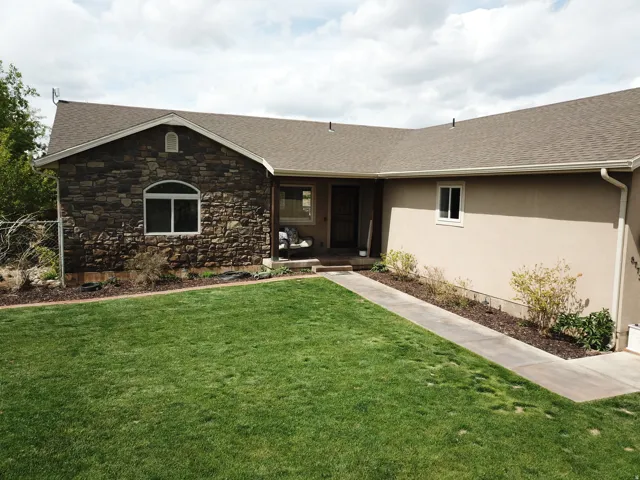 Entrance to property with roof with shingles, stucco siding, and stone siding