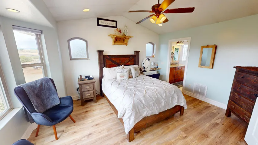 Primary Bedroom with light wood-style floors, vaulted ceiling, ensuite bath, and ceiling fan