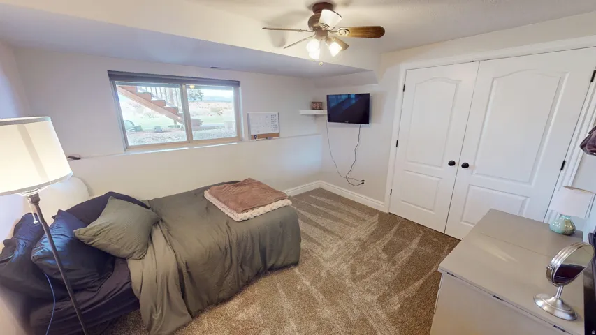Bedroom featuring dark colored carpet, a ceiling fan, and a closet