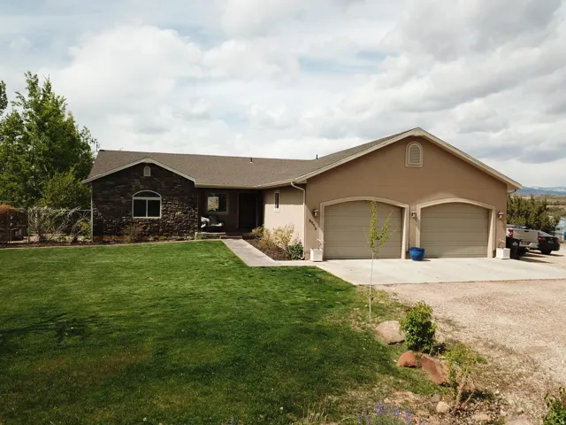 Ranch-style home featuring concrete driveway, a front lawn, stucco siding, a garage, and stone siding