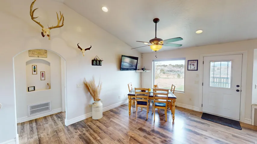 Dining area with vaulted ceiling, recessed lighting, light wood-style floors, arched walkways, and ceiling fan