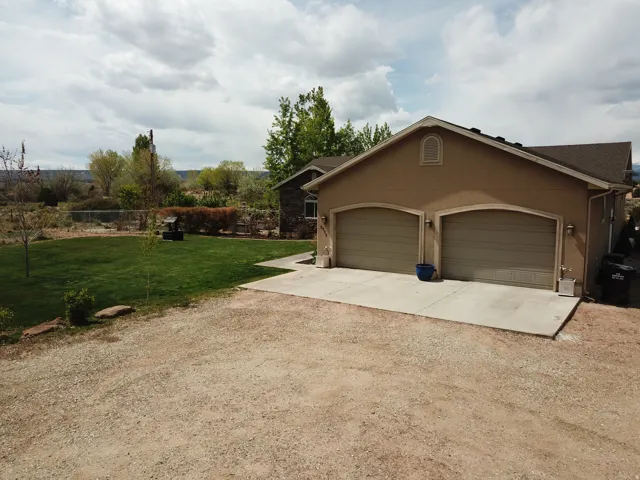 View of side of home with a lawn, driveway, stucco siding, and a garage