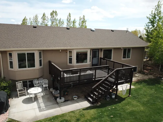 Rear view of property featuring a shingled roof, a wooden deck, and stucco siding