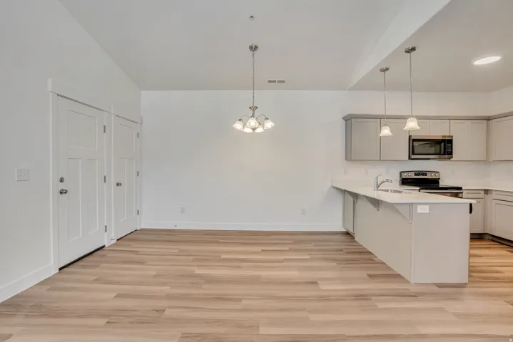 Kitchen with a kitchen breakfast bar, stainless steel appliances, a peninsula, and light wood-style flooring