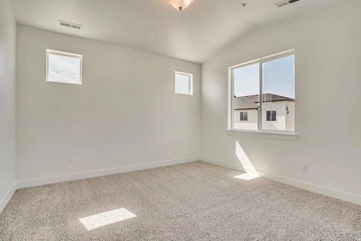 Empty room with vaulted ceiling and carpet flooring