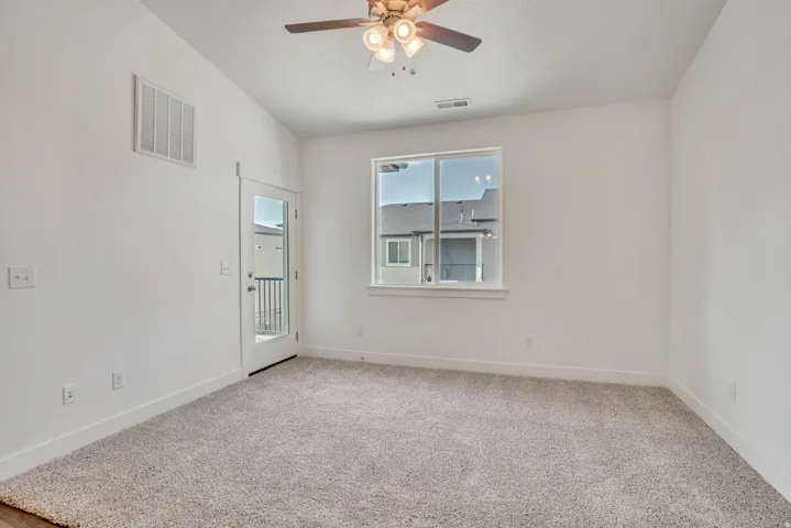 Empty room featuring light carpet, a ceiling fan, and lofted ceiling