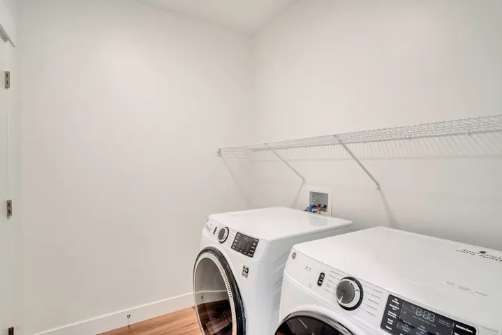 Laundry room featuring washing machine and clothes dryer and light wood-style flooring