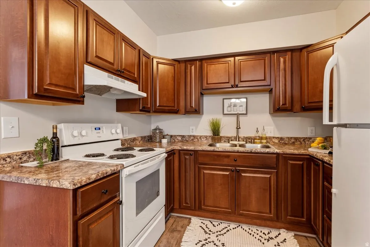 Kitchen featuring white appliances, wood finish cabinetry, and light wood-style flooring