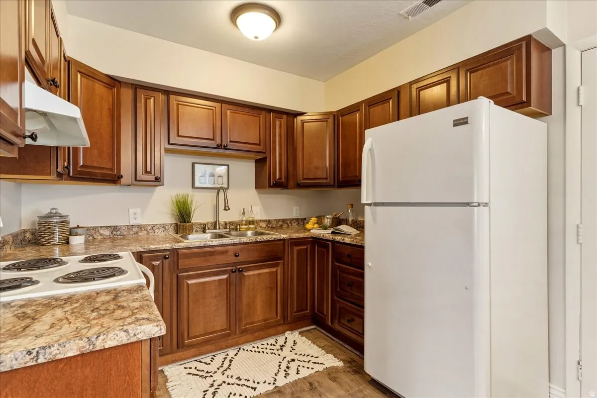 Kitchen featuring white appliances, wood finish cabinetry, light countertops, and light wood-style floors