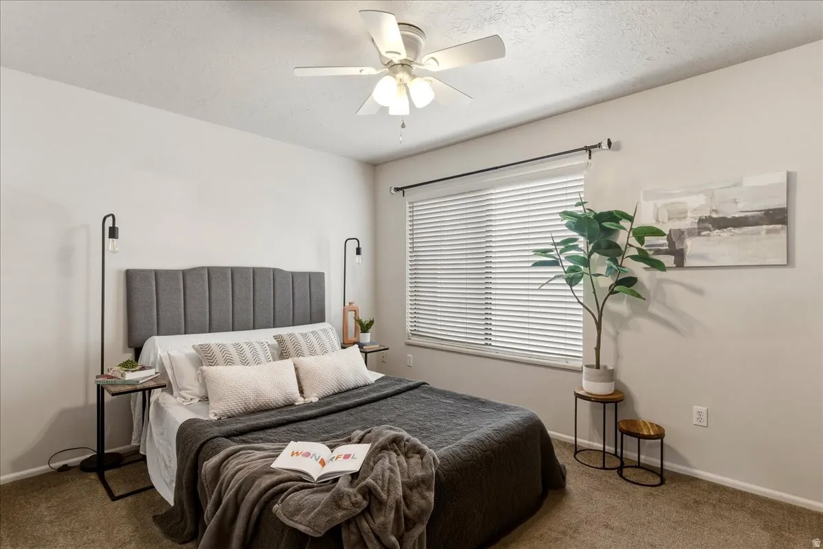 Carpeted bedroom with a textured ceiling and ceiling fan