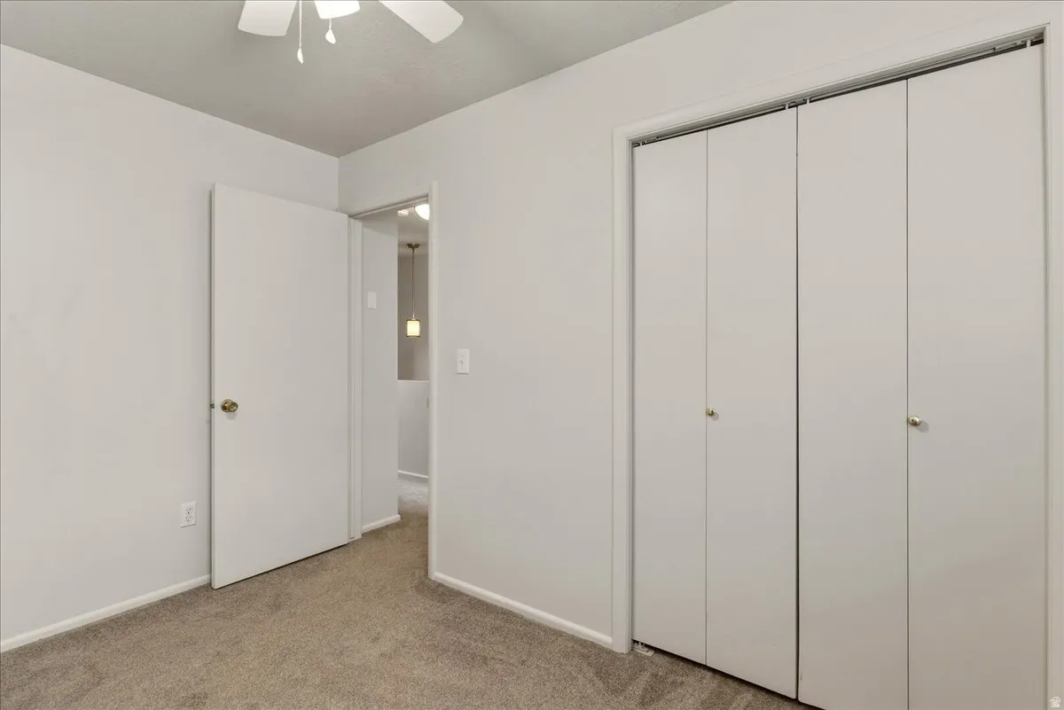 Unfurnished bedroom with light colored carpet, a closet, and ceiling fan
