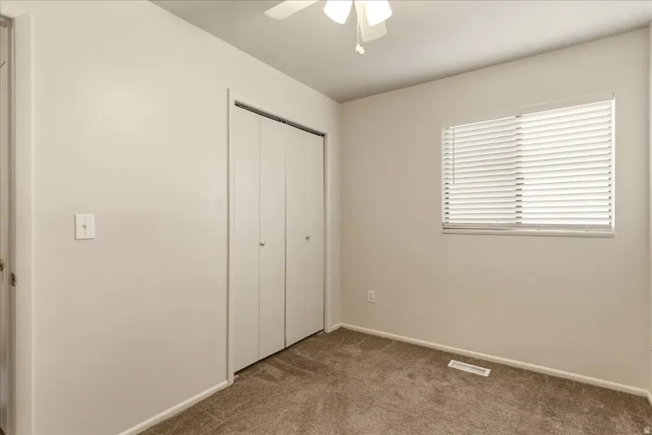 Unfurnished bedroom featuring a closet, carpet floors, and ceiling fan