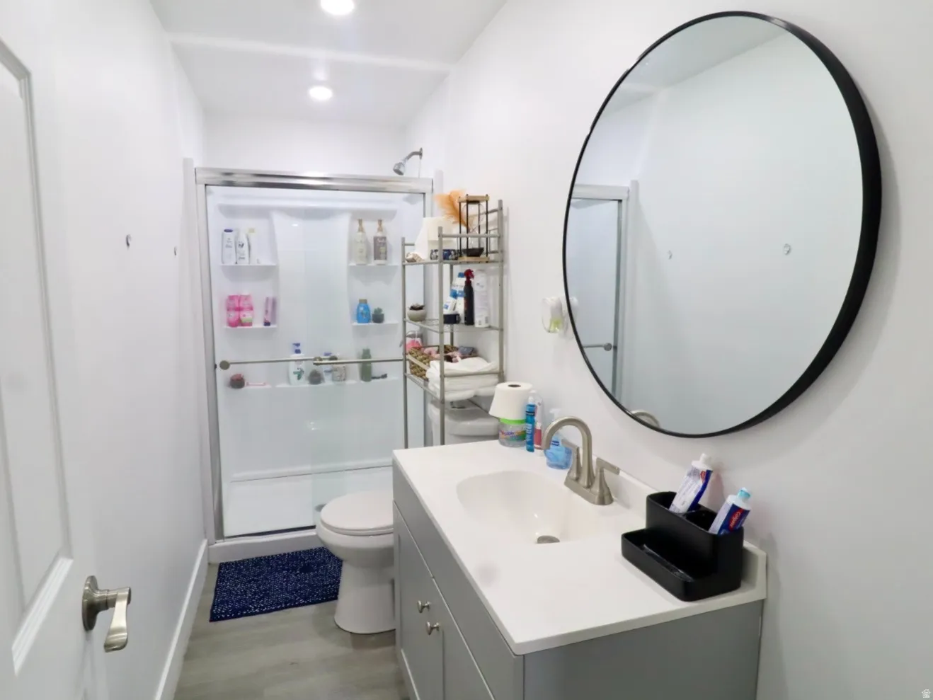 Full bath featuring vanity, a shower stall, and light wood-type flooring