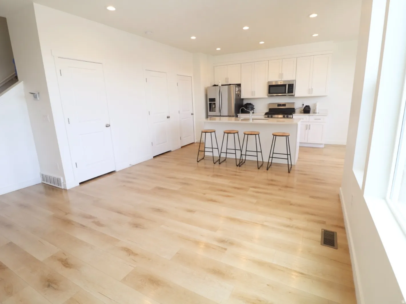 Kitchen featuring a breakfast bar area, stainless steel appliances, light wood-style flooring, a kitchen island with sink, and recessed lighting