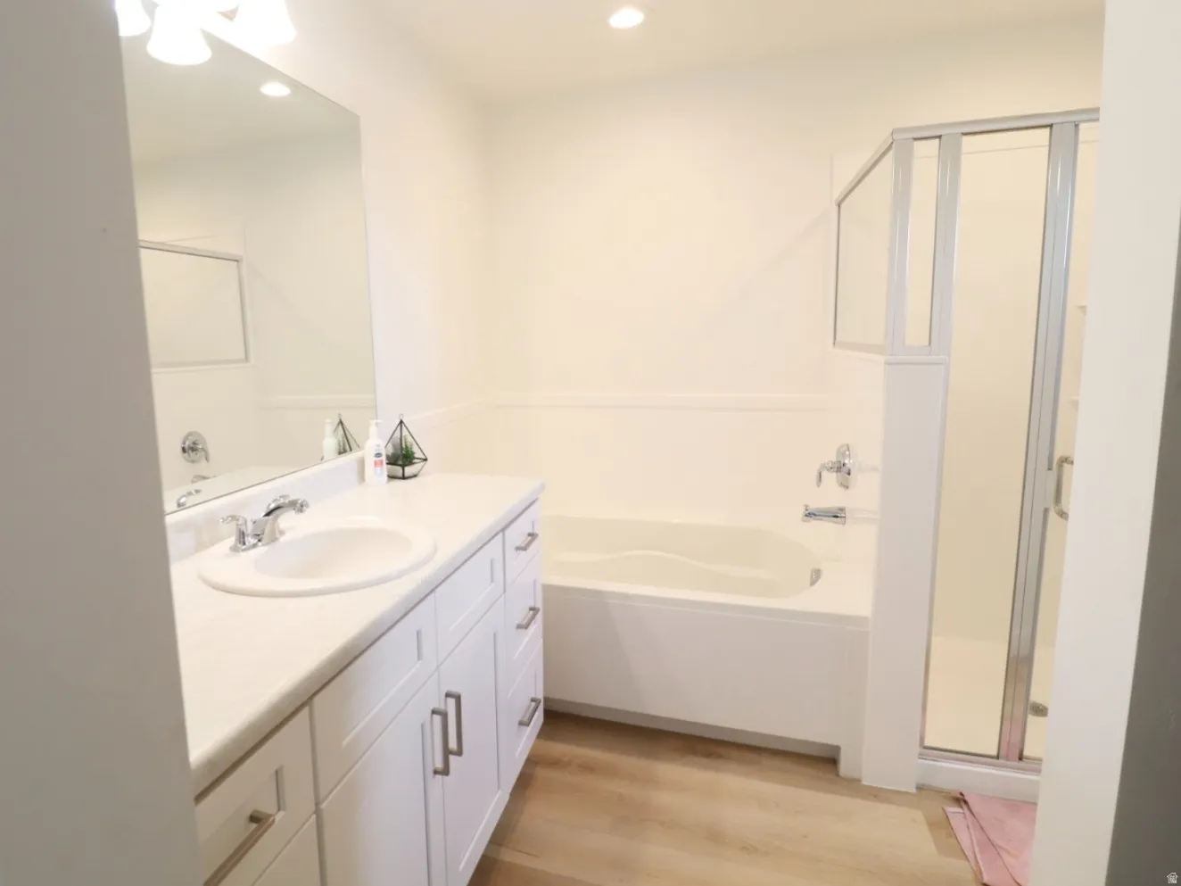 Bathroom with vanity, light wood finished floors, a stall shower, a garden tub, and recessed lighting