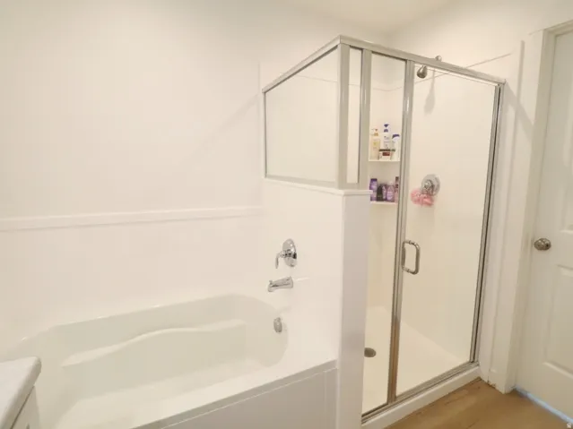 Bathroom with a garden tub, a stall shower, vanity, and light wood-style flooring