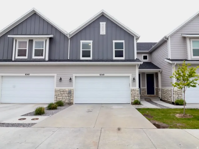 View of front facade with stone siding, board and batten siding, and a garage
