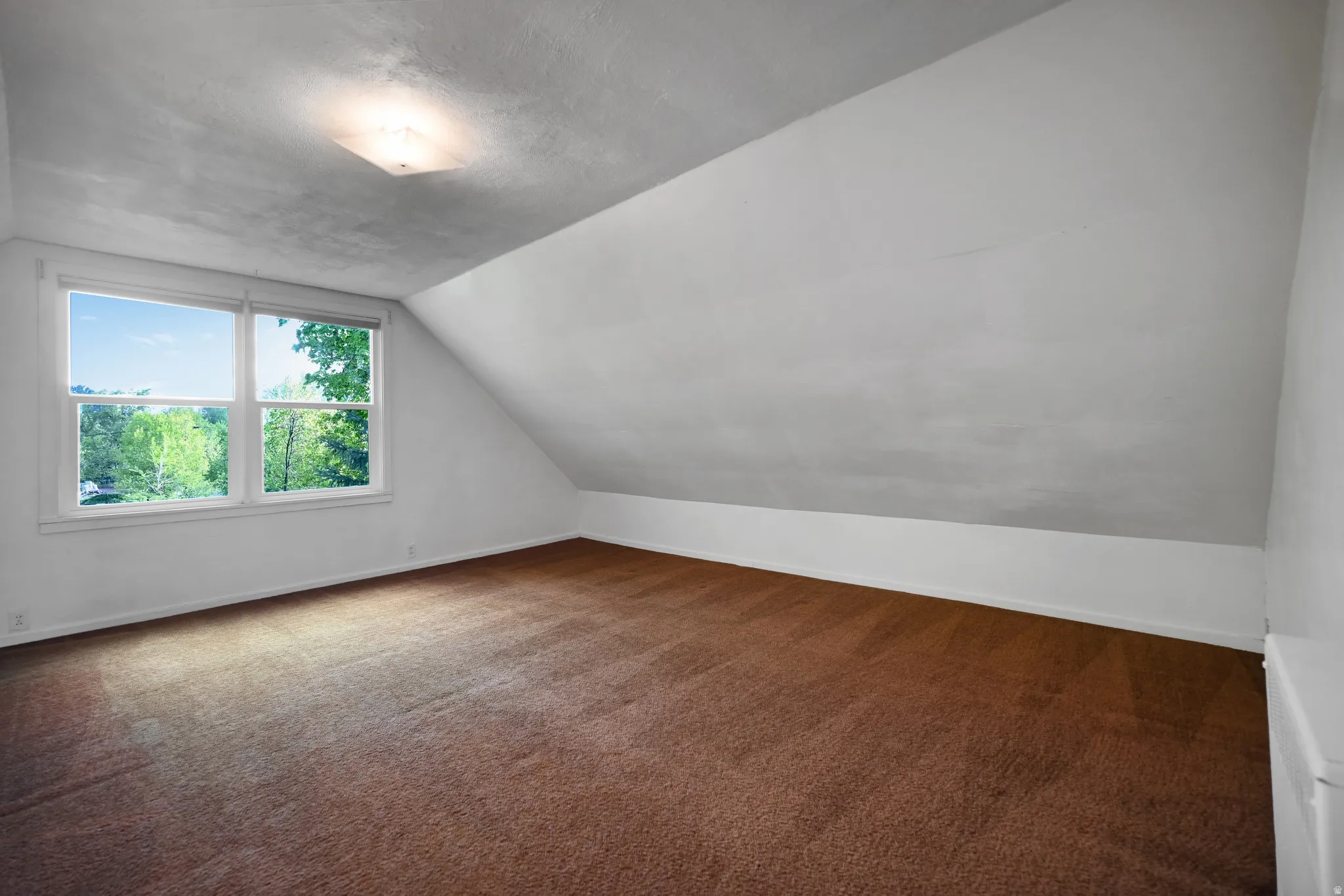 Bonus room featuring dark carpet and lofted ceiling