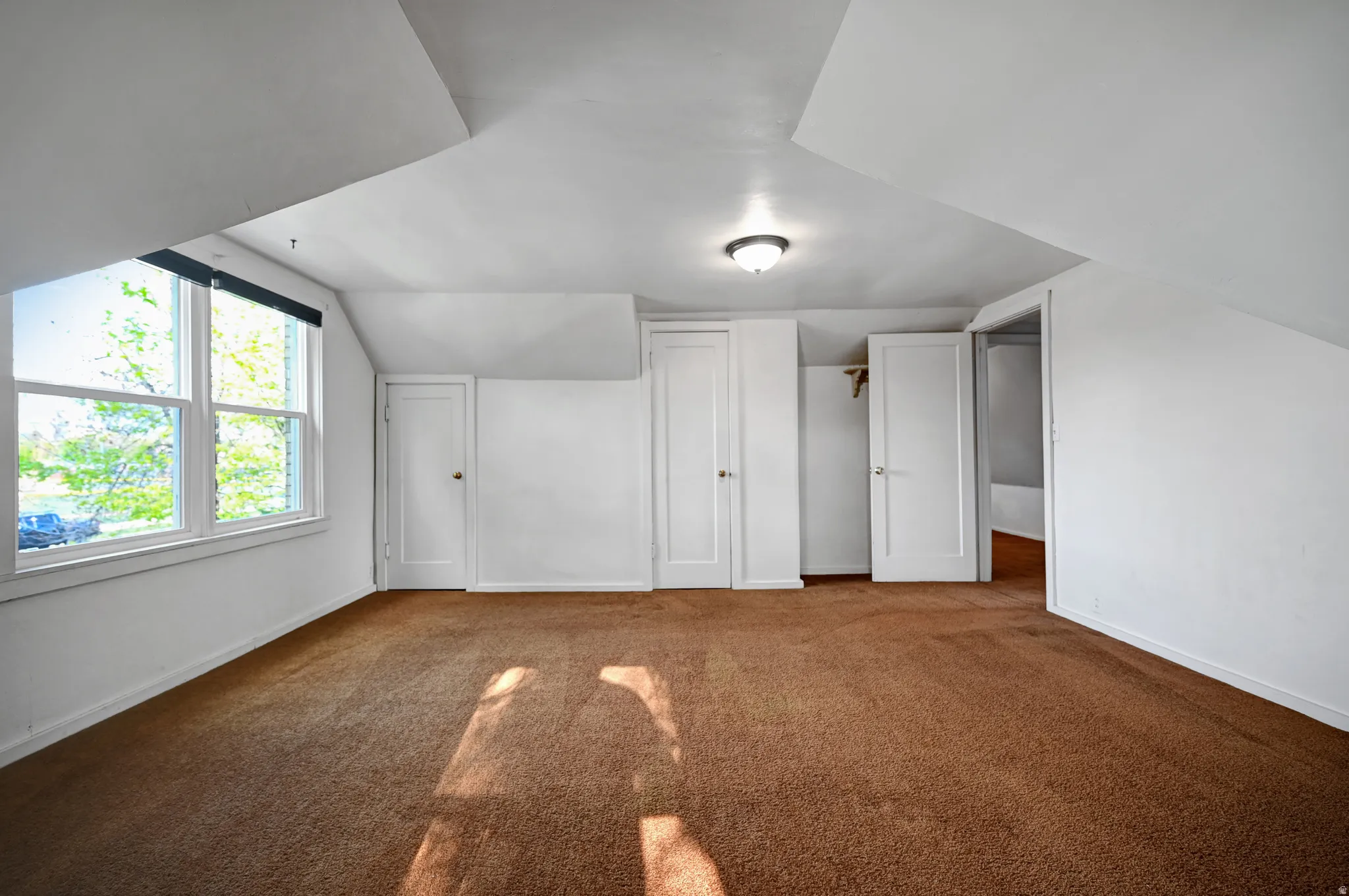 Bonus room featuring dark colored carpet and lofted ceiling