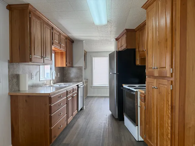 Kitchen with wood finish cabinetry, light countertops, electric range, dark wood-type flooring, and decorative backsplash