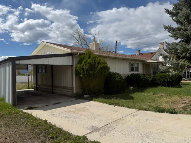 View of property exterior with a carport, concrete driveway, and a lawn