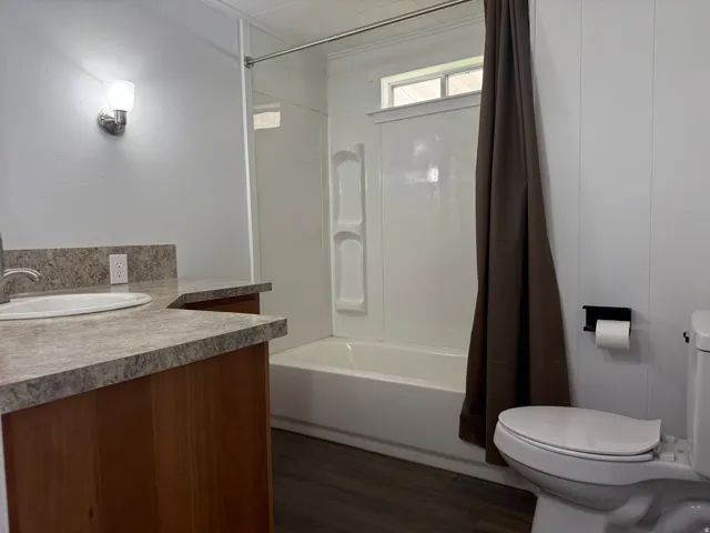 Full bath with vanity, shower / tub combo, and dark wood-style floors