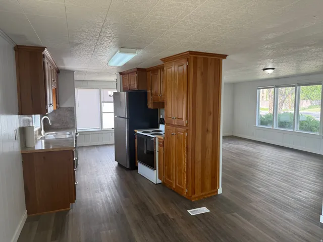 Kitchen featuring wood finish cabinetry, range with electric stovetop, light countertops, dark wood-type flooring, and plenty of natural light