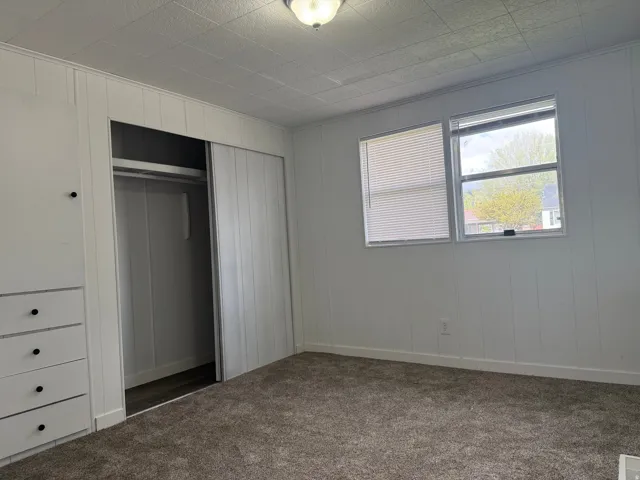 Unfurnished bedroom with a closet and dark colored carpet