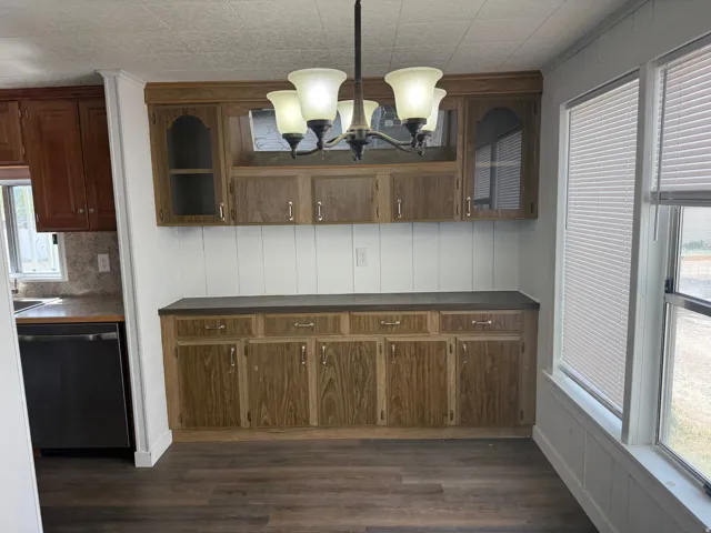 Unfurnished dining area featuring a chandelier and dark wood-style floors