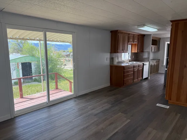 Kitchen with dark wood-style flooring, wood finish cabinetry, stainless steel appliances, light countertops, and backsplash