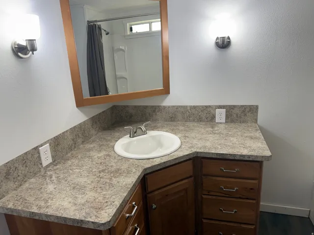 Full bath featuring vanity, curtained shower, and a textured wall