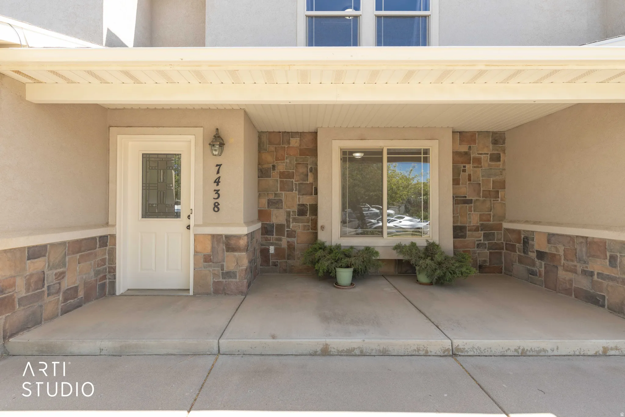 Property entrance with stone siding, stucco siding, and a porch