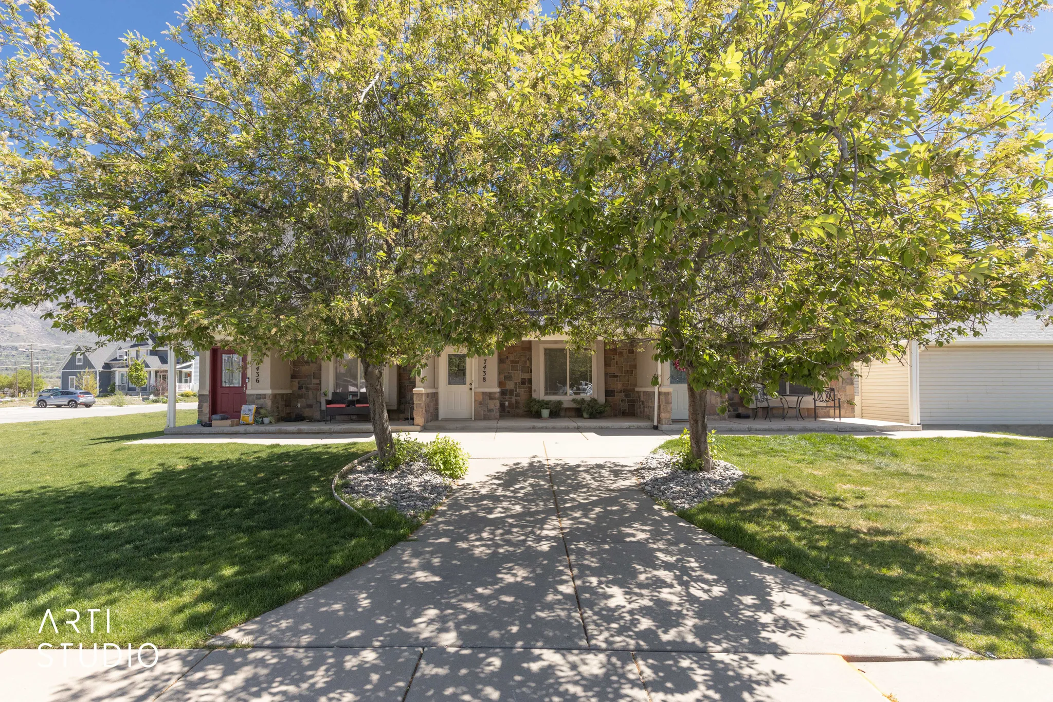View of property hidden behind natural elements featuring a front yard and stone siding