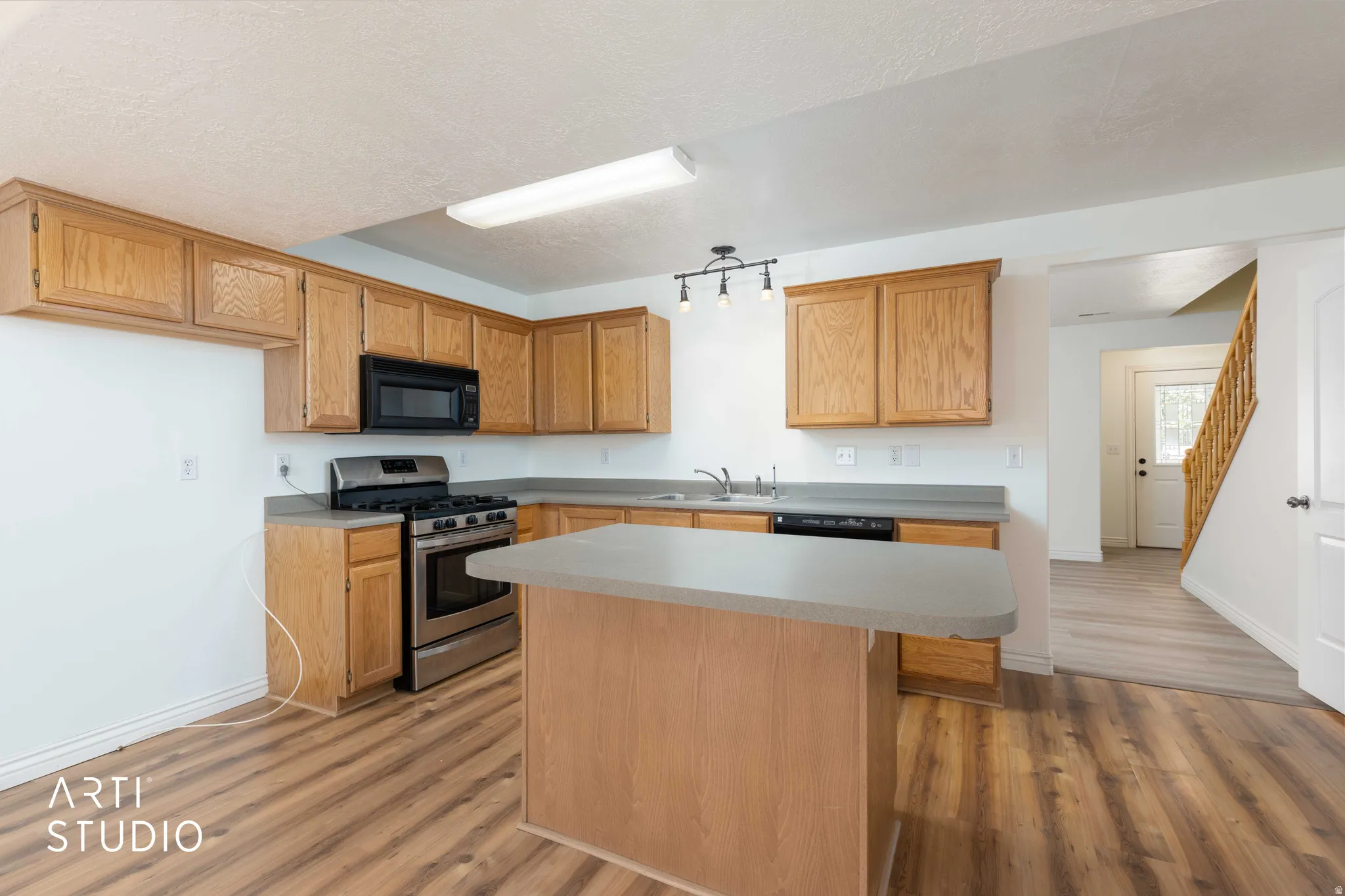 Kitchen with a kitchen island, light countertops, stainless steel range with gas stovetop, and light wood-style flooring